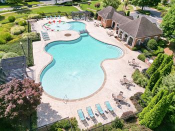 an aerial view of a resort style pool with chairs and a building at The Crest at Sugarloaf, Lawrenceville, 30044